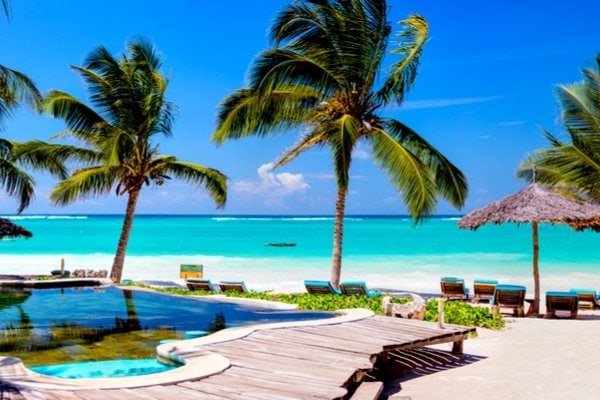 View of luxury hotel with palm trees, swimming pool and beach in Mexico.